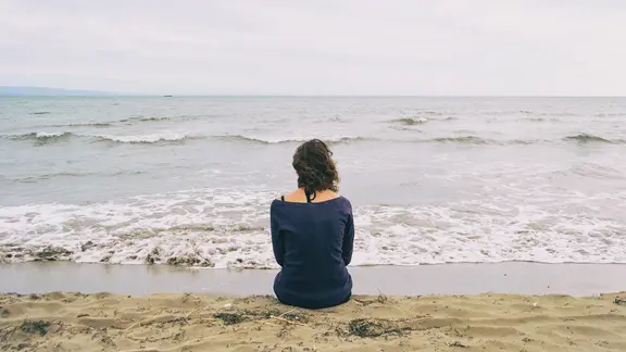 Eine Frau sitzt am Meer.