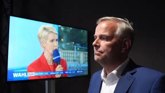 Holm blickt im ARD-Wahlstudio auf einen Monitor, auf dem Manuela Schwesig zu sehen ist.