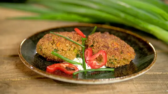 Zwei Gemüsebratlinge mit Paprika und Schnittlauch auf einem Teller angerichtet.