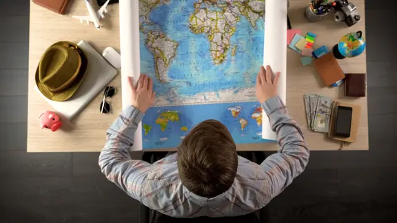 Ein Mann sitzt über einer Weltkarte. | Colourbox, Motortion Ein Mann sitzt über einer Weltkarte.