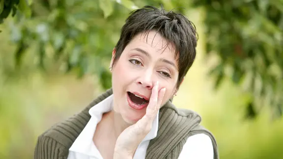 Frühjahrsmüdigkeit: Frau draußen in der Natur gähnt. 