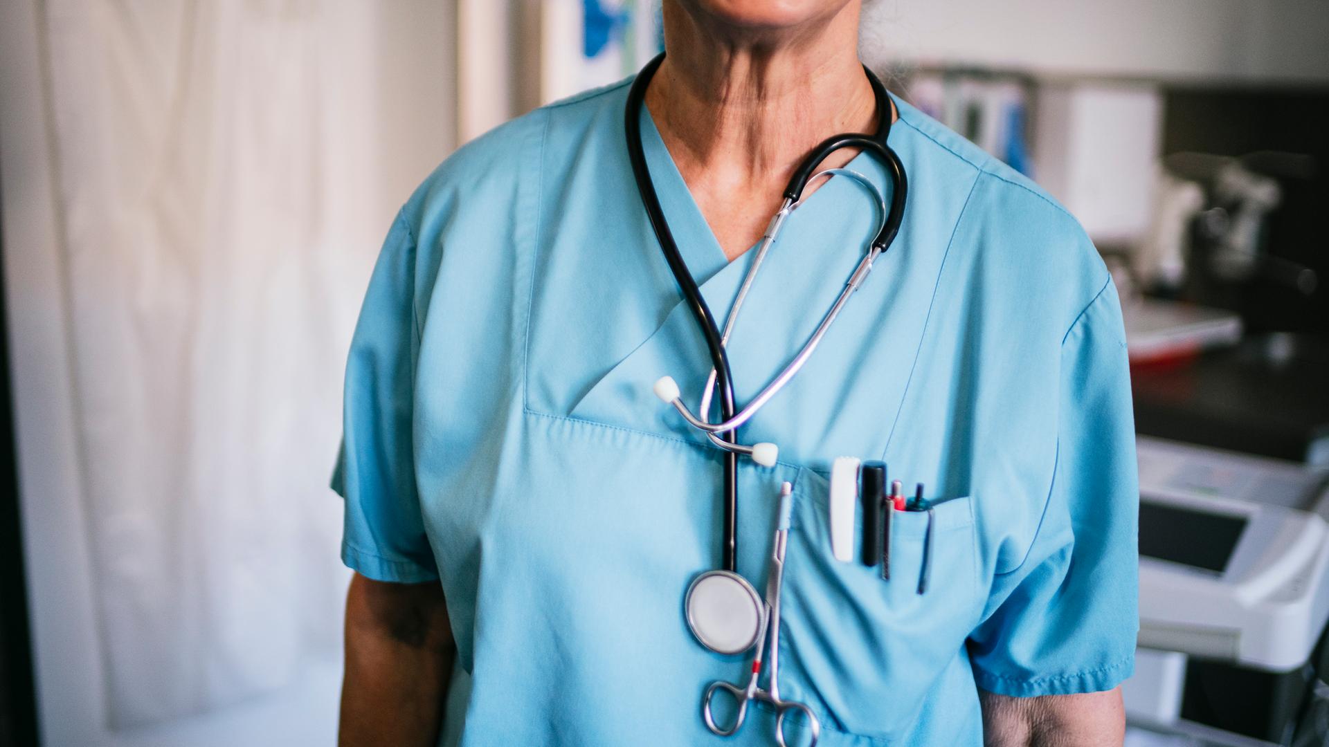 Das Bild zeigt den Oberkörper eines Pflegepersonals in einem Krankenhaus. | NDR, Julius Matuschik