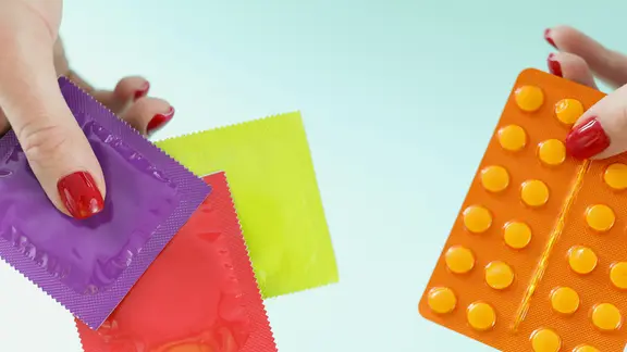 Verhütungsmittel: Frauenhände halten die Pille und Kondome.