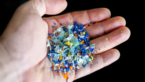 Jemand hält eine Handvoll verschiedener Mikroplastik-Teilchen in die Kamera.