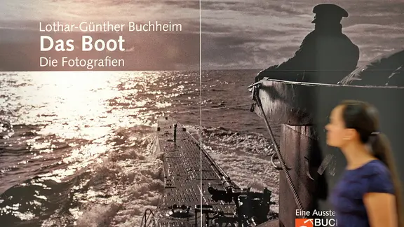2011 ist im Marinemuseum Wilhelmshaven eine Ausstellung zu Lothar-Günther Buchheims U-Boot-Fotos zu sehen. | picture alliance / dpa , Carmen Jaspersen Eine Besucherin geht am 4. Mai 2011 an dem Plakat zur Ausstellung "Das Boot" von Lothar-Günther Buchheim im Marinemuseum in Wilhelmshaven vorbei.