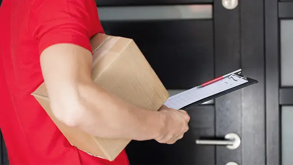 Paketbote an einer Haustür.