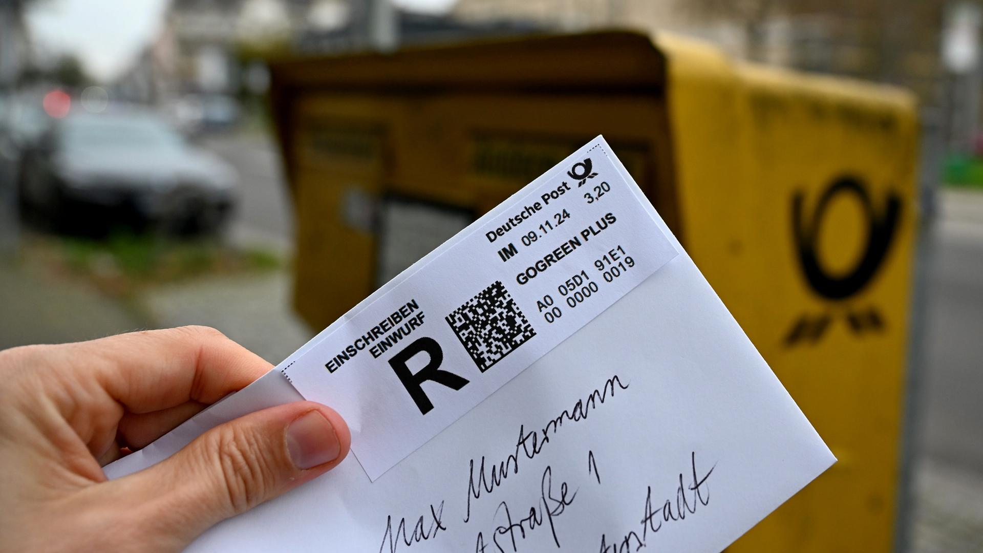 Ein Mann hält ein sogenanntes Einwurf-Einschreiben vor einen Briefkasten | picture alliance/dpa, Wolf von Dewitz