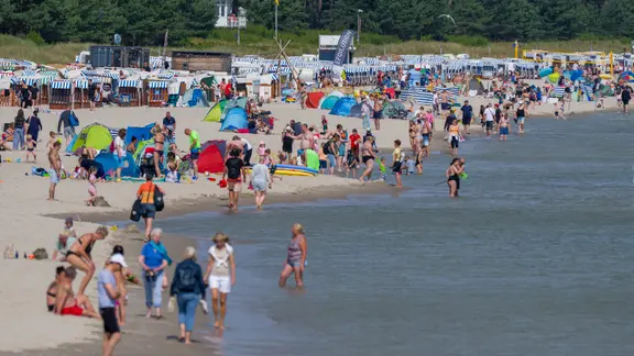 Touristen nutzen das hochsommerliche Wetter am Strand auf der Insel Rügen zum Sonnen und Baden.
