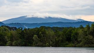 Blick über einem Okerteich zum Brocken im Nebel.