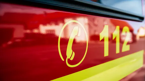 Der Notruf "112" steht in gelber Schrift an einem roten Feuerwehrfahrzeug.
