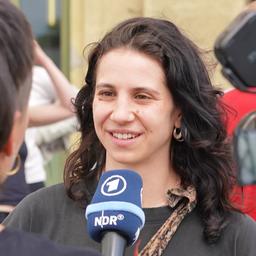 Eine junge Frau spricht in ein Mikrofon.