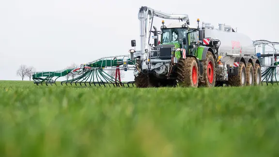 Ein Landwirt düngt mithilfe der Schleppschlauchtechnik ein Feld.