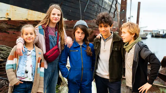 Gruppenbild mit Clarissa, Alice, Hanna, Tarun und Jonny vor einem alten Schiff.