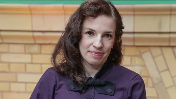 Eine junge Frau blickt lächelnd in die Kamera