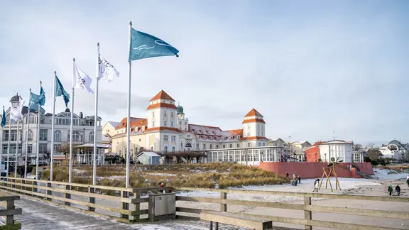 Spaziergänger nutzen das sonnige Wetter für einen Ausflug am Ostseestrand von Binz im Winter.
