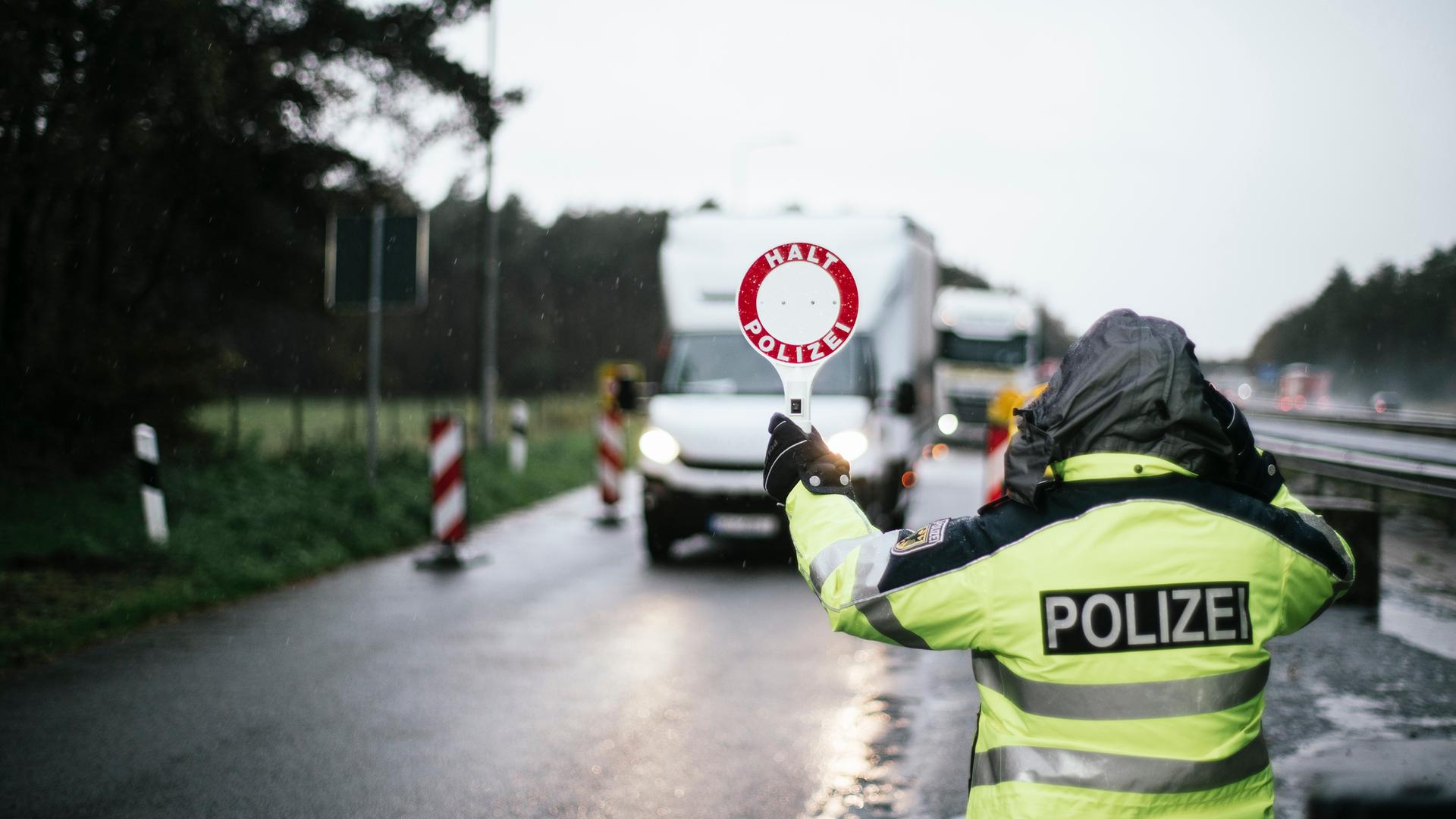 Eine Einsatzkraft der Polizei kontrolliert den Straßenverkehr bei schlechtem Wetter. | NDR, Julius Matuschik