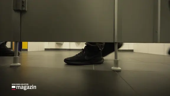 Jemand steht vor eine Schultoilettenkabine.