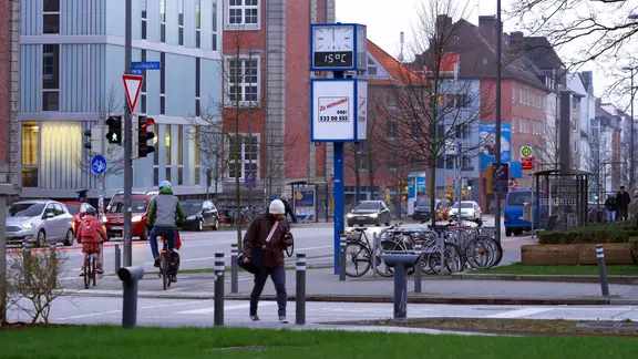 Eine Straßenszene in Kiel. In der Mitte ist eine große Uhr zu sehen.