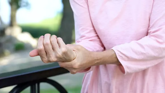 Ein Frau hält sich vor Schmerzen das Handgelenk.
