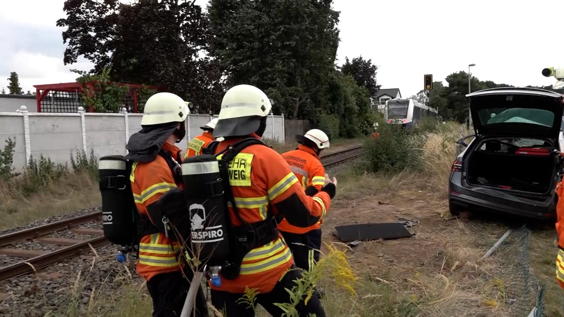 Einsatzkräfte der Feuerwehr stehen vor einer Unfallstelle an einem Bahnübergang. | NonstopNews