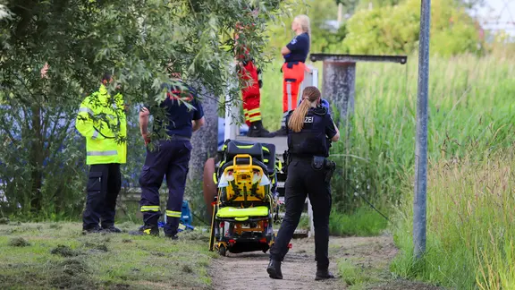 Rettungssanitäter, Polizei und Feuerwehr stehen an einem Gewässer.