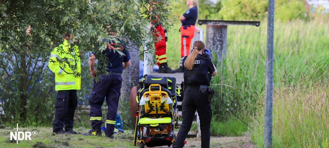 Rettungssanitäter, Polizei und Feuerwehr stehen an einem Gewässer. | Florian Sprenger Rettungssanitäter, Polizei und Feuerwehr stehen an einem Gewässer.