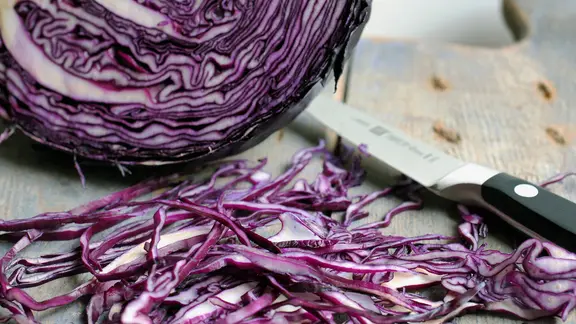 Selbst gekochtes Rotkraut ist nicht nur frischer als fertiges, man behält auch die Kontrolle über den Zuckergehalt. | NDR, Anja Deuble Ein Messer liegt neben frisch geschnittenem Rotkohl.