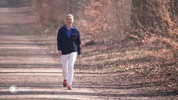 Eine Frau spaziert durch einen Wald.