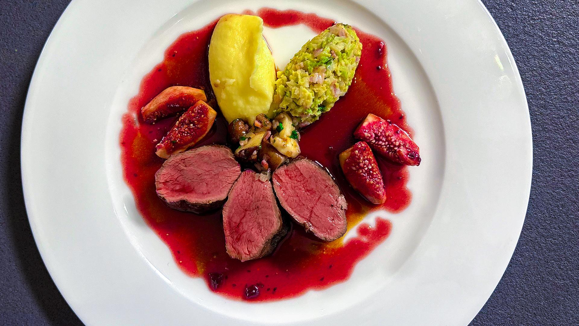 Rosa gegarter Rehrücken mit Nocken von Kartoffelpüree und Rahmwirsing sowie Pilzen, Feigen und roter Soße auf einem Teller angerichtet | NDR