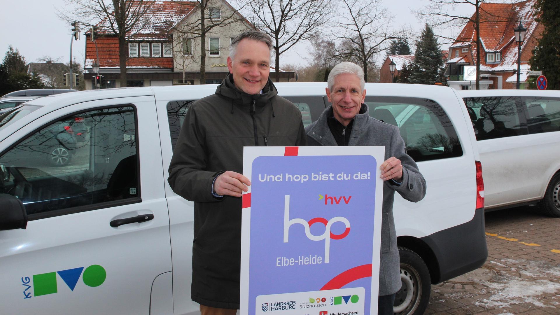 Zwei Männer schauen in die Kamera und halten ein Plakat zum Angebot 