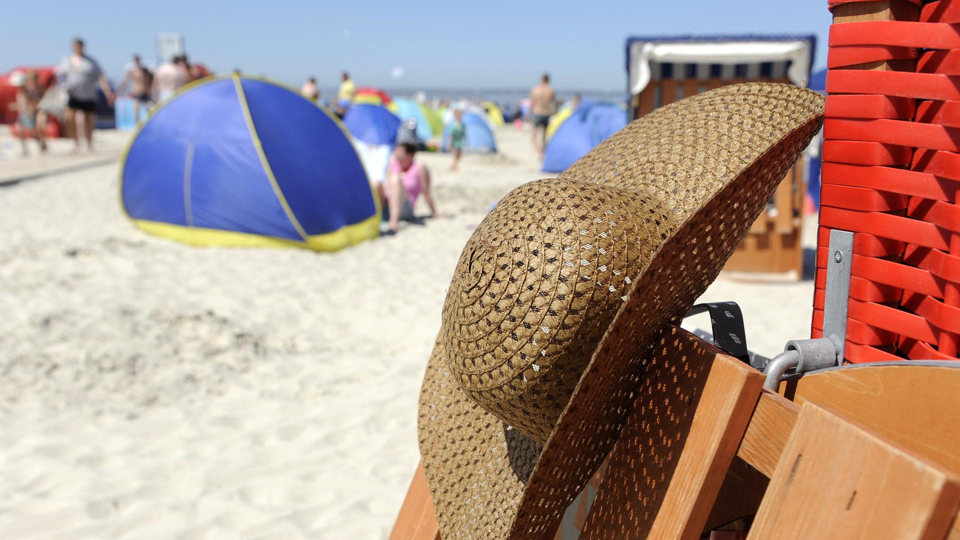 Bei hochsommerlichen Temperaturen hängt am 21. Juli 2013 der Strohhut einer Nordseeurlauberin an einem Strandkorb in Bensersiel. | picture alliance/dpa, Ingo Wagner