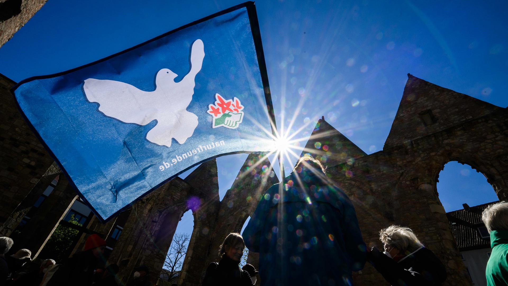 Demonstrierende mit Friedenstaube-Flagge bei einem Ostermarsch 2022. | dpa, Julian Stratenschulte