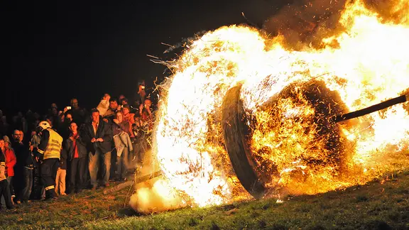 Oster-Tradition: Ein brennendes fast 280 Kilogramm schweres Eichenrad rollt am 12.04.2009 in Lügde (Kreis Lippe) nahe der niedersächsischen Landesgrenze bergab vorbei an Zuschauern in das Emmertal. | picture alliance / dpa | Peter Steffen Oster-Tradition: Ein brennendes fast 280 Kilogramm schweres Eichenrad rollt am 12.04.2009 in Lügde (Kreis Lippe) nahe der niedersächsischen Landesgrenze bergab vorbei an Zuschauern in das Emmertal.
