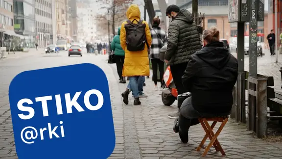 Menschen stehen in einer Warteschlange, eine Person sitzt auf einem Stuhl. Daneben das Logo der Ständigen Impfkommission STIKO