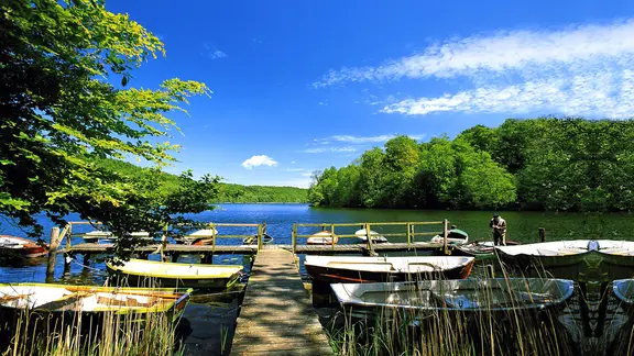 Boote liegen bei schönem Sommerwetter an einem Holzsteg am Ukleisee nahe Eutin.