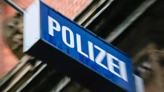An einer Hausfassade hängt ein Leuchtschild mit der Aufschrift Polizei.