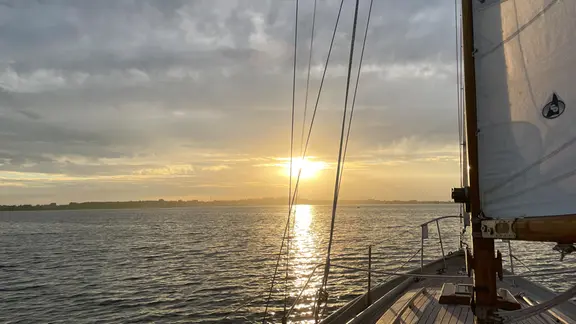 Ein Segelboot auf der Ostsee, das Richtung Sonne fährt.