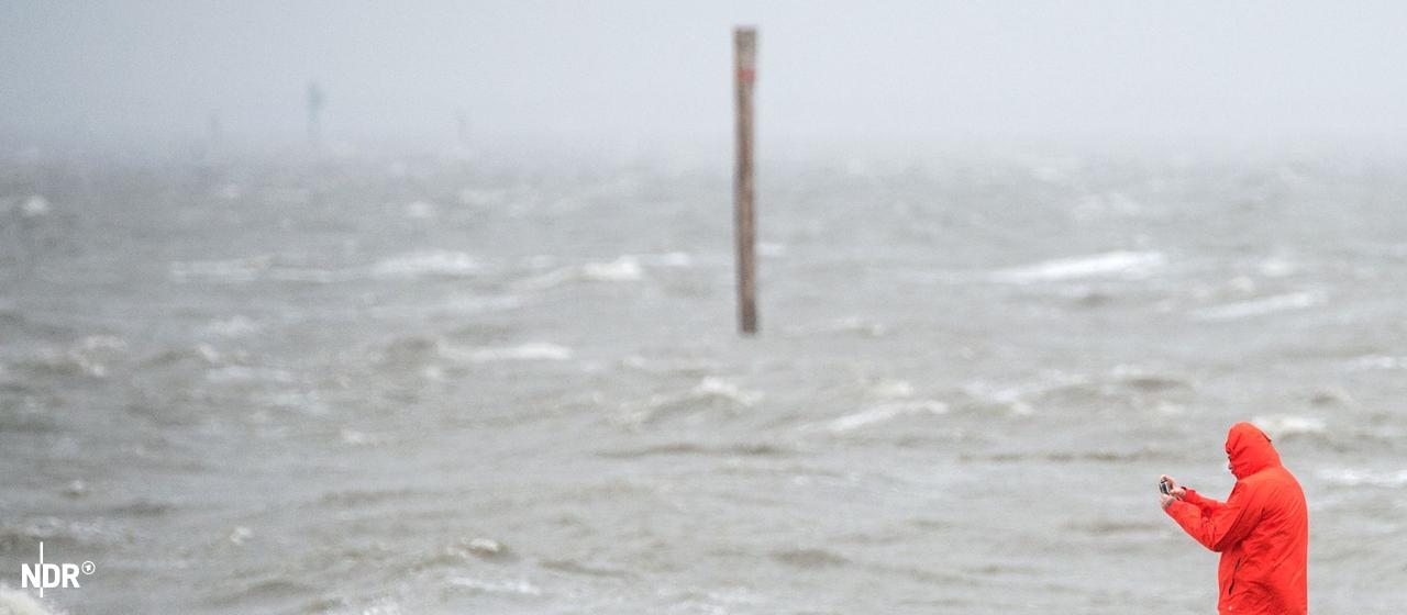 Sturmflutsaison beginnt: Ein Mann fotografiert an einem Strandabschnitt die peitschenden Wellen der Nordsee. (Archivbild)