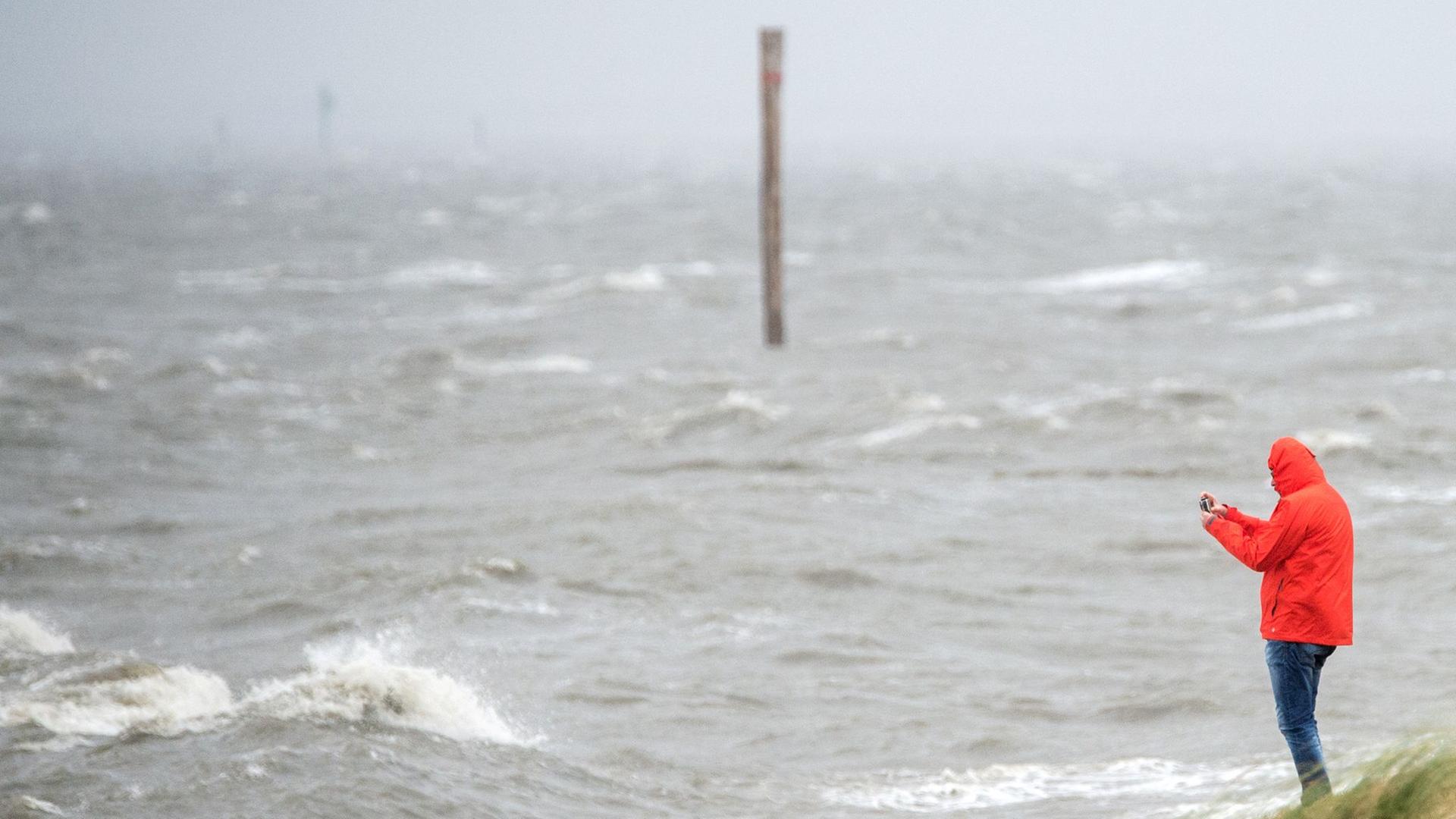Sturmflutsaison beginnt: Ein Mann fotografiert an einem Strandabschnitt die peitschenden Wellen der Nordsee. (Archivbild) | dpa, Hauke-Christian Dittrich