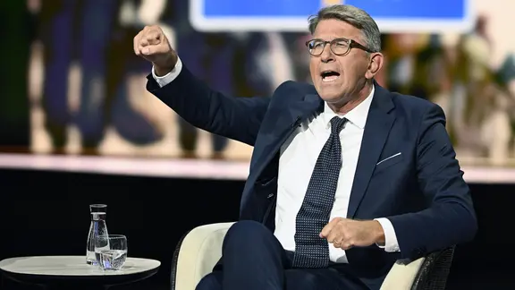 Wolfram Weimer sitzt auf einem Sessel und gestikuliert mit seinen Händen, die zu Fäusten geformt sind.