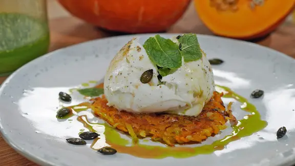 Kürbis-Rösti mit Mozzarella und Lauch-Öl auf einem weißen Teller