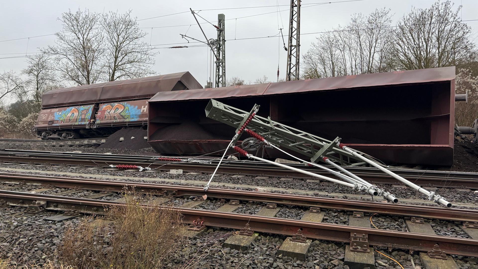 Ein Güterzug liegt auf Gleisen umgekippt auf der Seite neben einem umgekippten Mast. | HannoverReporter