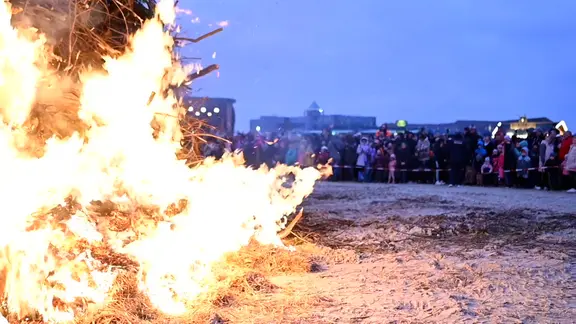 Menschen stehen um ein großes Osterfeuer in Norddeich herum. | TeleNewsNetwork Menschen stehen um ein großes Osterfeuer in Norddeich herum.