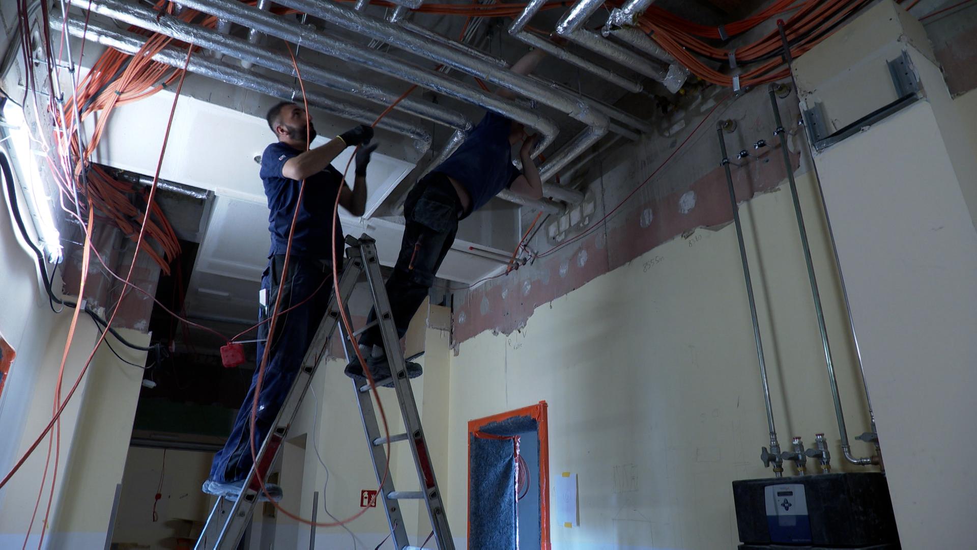 Ein Mann steht auf einer Leiter, der der Decke hängen Kabel. | NDR