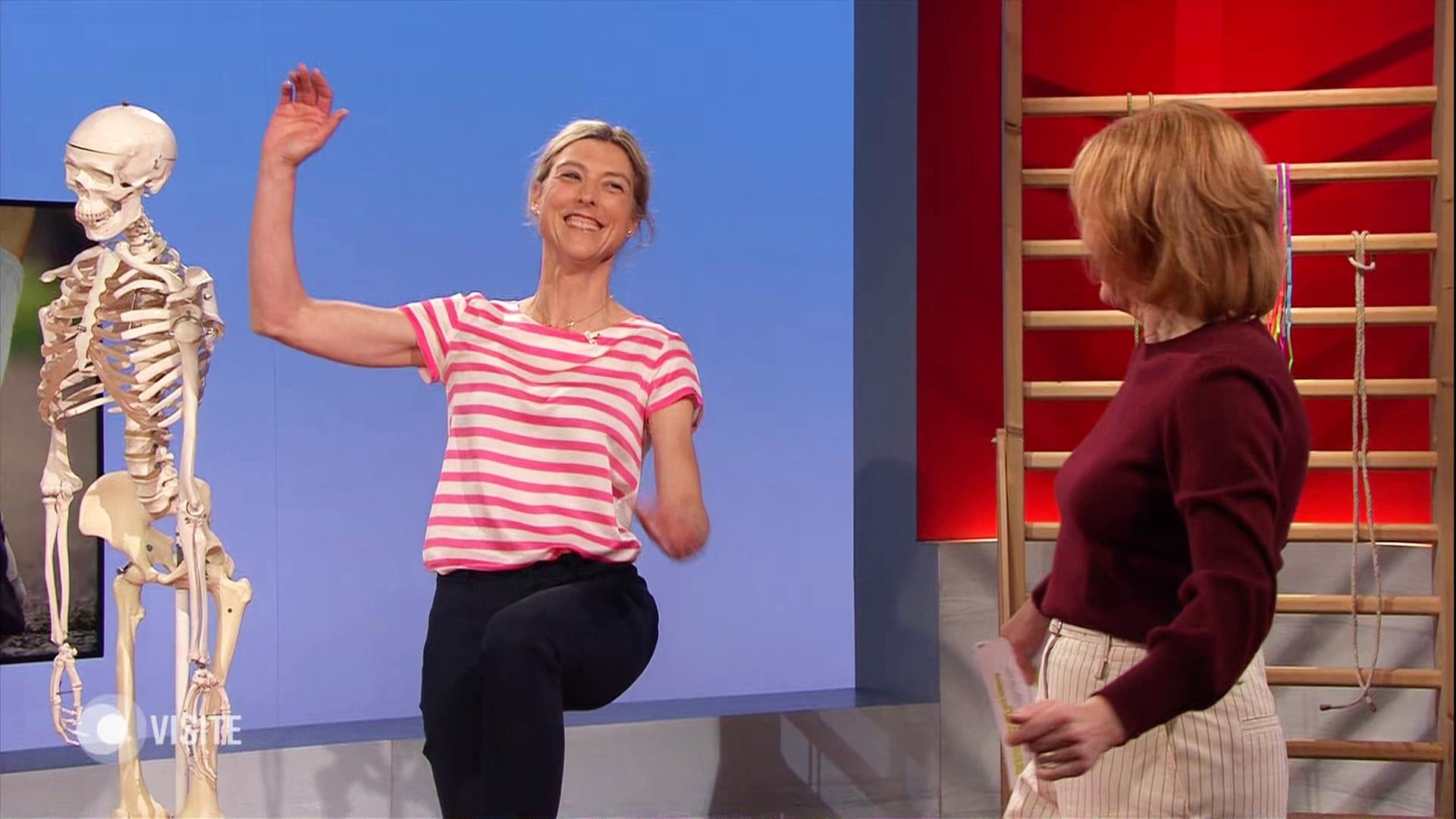 Eine Person hebt die Arme und das rechte Bein. | Screenshot