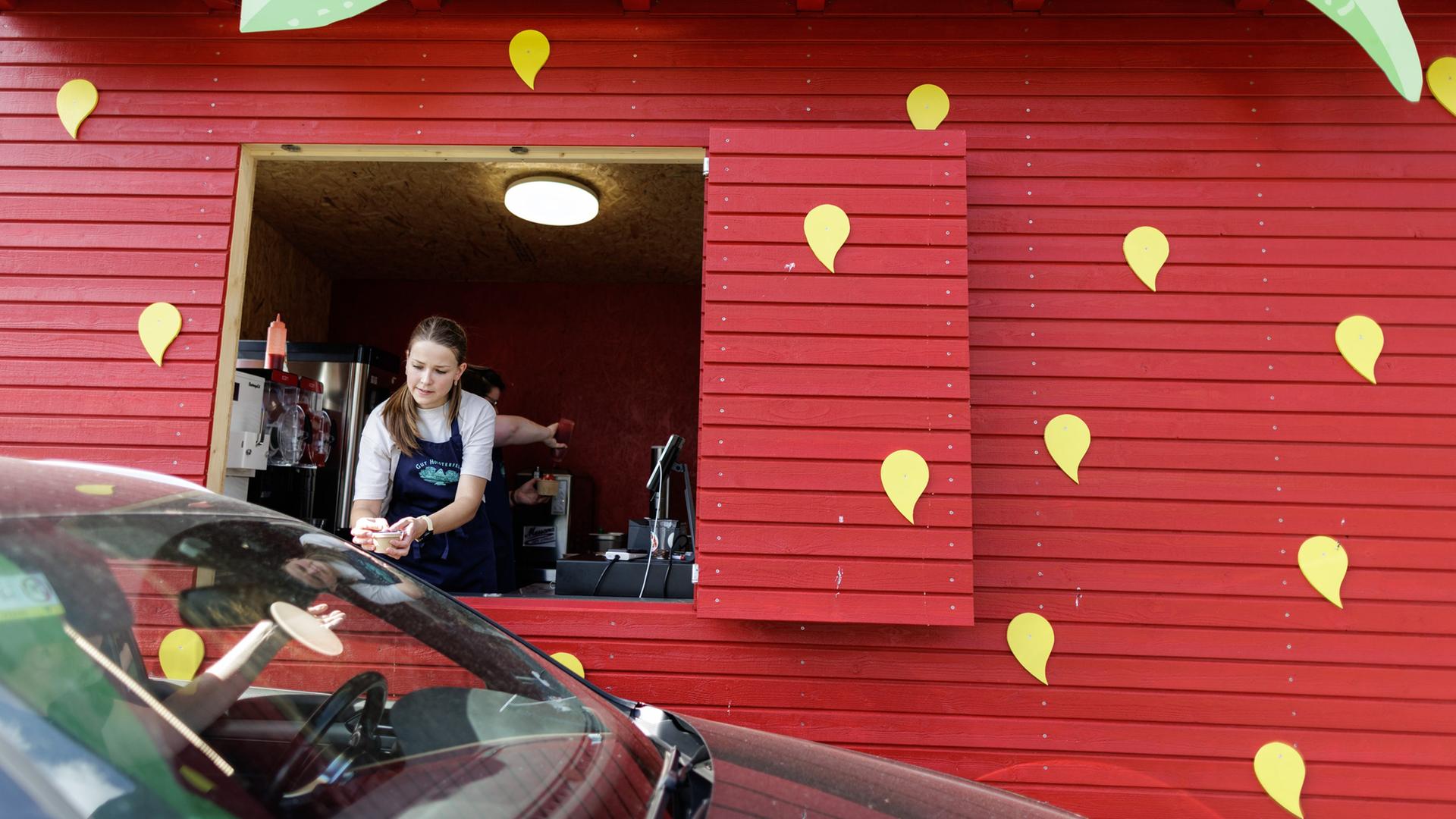 Eine Mitarbeiterin verkauft einem Autofahrer ein Spaghetti-Eis. | picture alliance/dpa, David-Wolfgang Ebener