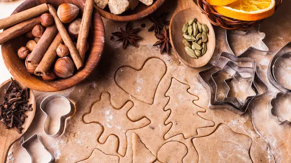 Weihnachtliche Backutensilien mit ausgerolltem Teig und Ausstechförmchen.