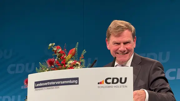 Johann Wadephul lächelt an einem Rednerpult auf einem Treffen der Landesvertreter der Nord-CDU in Neumünster.