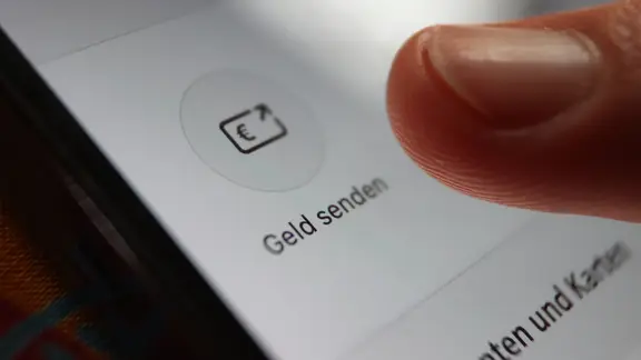 Ein Daumen im Nahaufnahme drückt auf ein Symbol auf einem Smartphone.