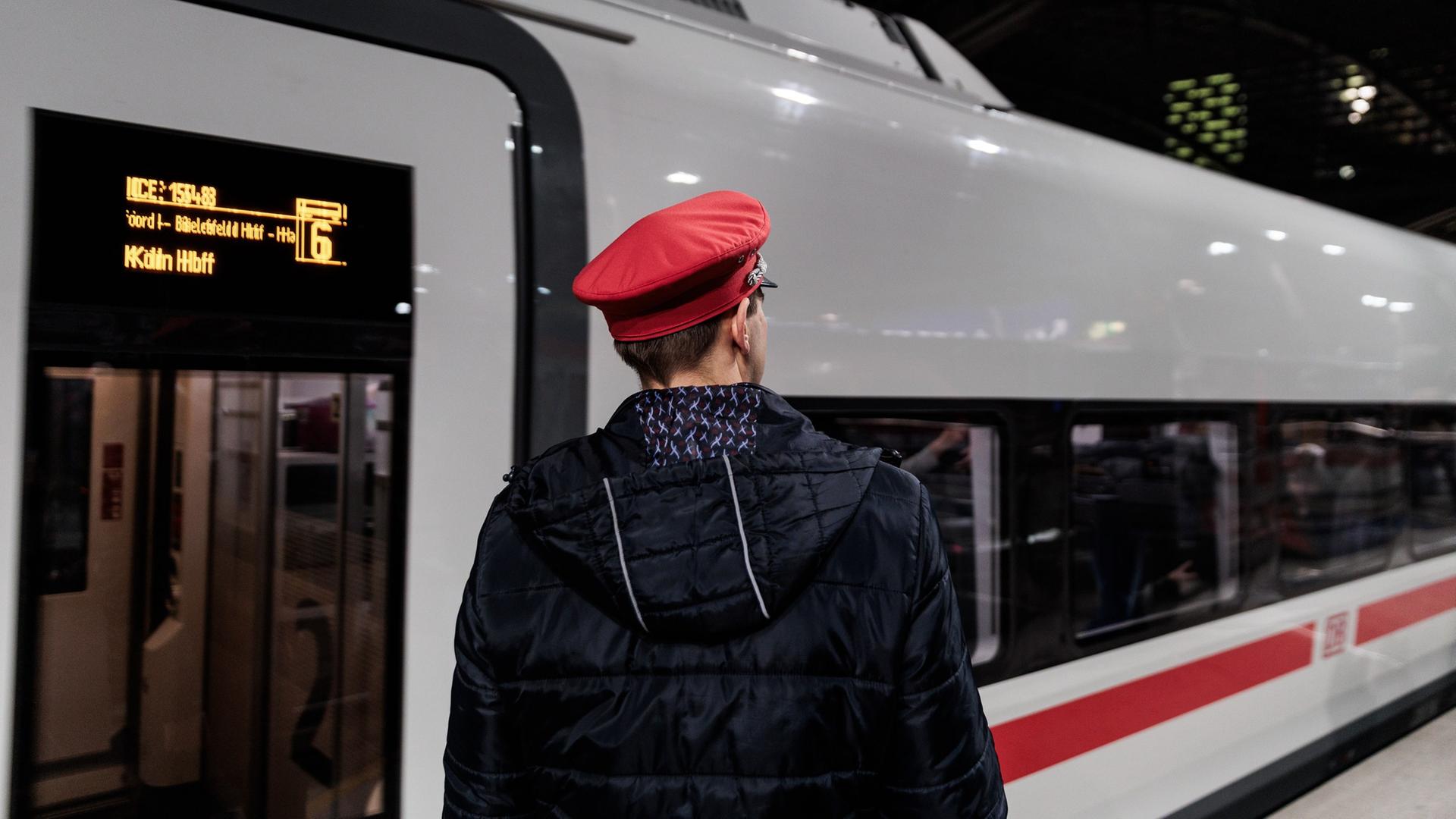 Ein Zugbegleiter steht an einem Bahnhof vor einem ICE. | picture alliance/dpa | Carsten Koall